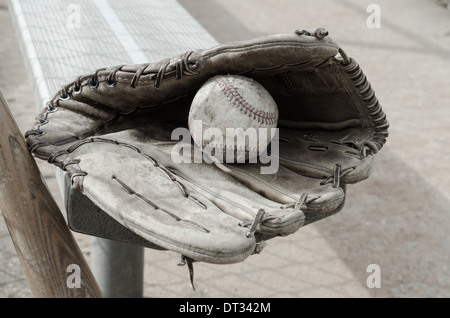 Baseball mit Ball und Handschuh auf Bank im Einbaum mit Fledermaus vergangener Zeiten. Stockfoto