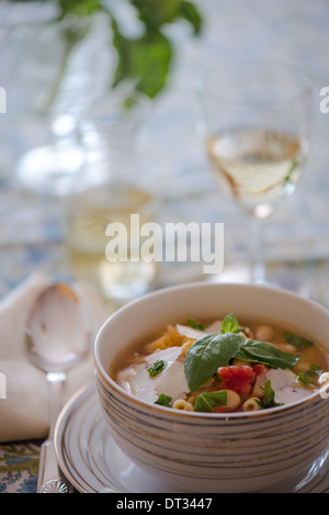 Einen Teller Pasta und Bohnen Suppe gesetzt auf eine Tabelle mit Weißwein Stockfoto