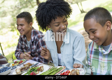 Ein Familien-Picknick in einer schattigen Wald A Frau und zwei jungen sitzen, lachen Stockfoto