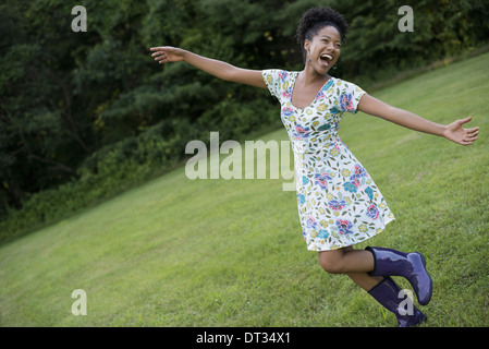 Eine junge Frau in einem Sommerkleid mit ihre Arme ausgestreckt feiert Freiheit Stockfoto