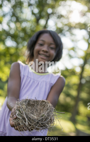 Ein Kind ein junges Mädchen Lächeln auf den Lippen und ein Vogelnest in ihren Händen hielt Stockfoto