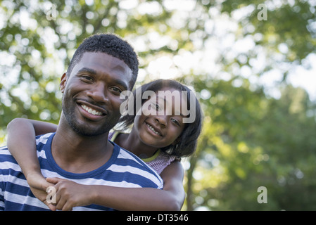 Ein Mann ein Kind eine Huckepack im Schatten der Bäume an einem Sommertag Stockfoto