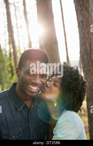 Ein paar eine junge Frau, die einen Mann auf die Wange küssen Stockfoto