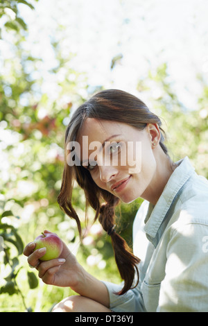 Eine junge Frau hält einen frisch gepflückten Apfel vom Baum Stockfoto