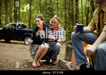 Drei Personen sitzen um ein Lagerfeuer in der Dämmerung Stockfoto