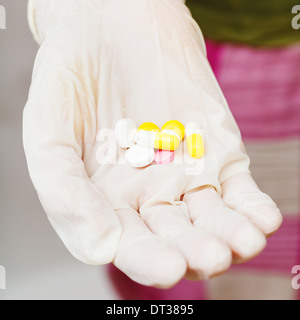 einige Tabletten in Patienten behandschuhte Hand hautnah Stockfoto