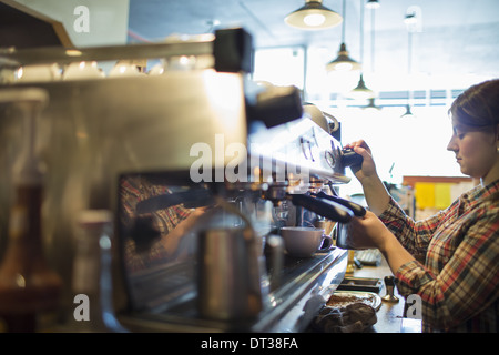 Eine Person, Barista Kaffee kochen und Aufschäumen mit einem Heisswasser-/ Dampfdüse, für einen Cappuccino. Coffee-Shop. Stockfoto