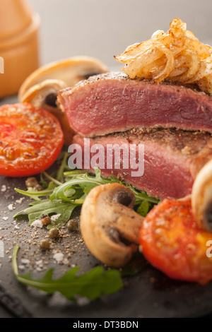 Seltene Steak mit Tomaten und Champignons Stockfoto