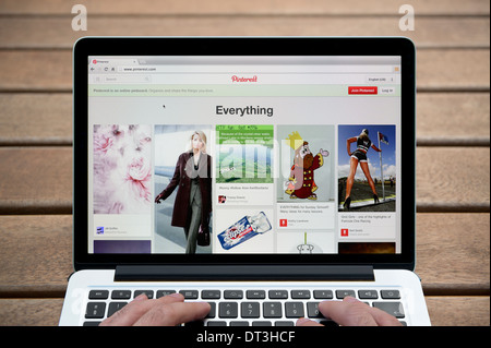 Die Pinterest-Website auf einem MacBook Hintergrund eine Holzbank im Freien einschließlich eines Mannes Finger (nur zur redaktionellen Verwendung). Stockfoto