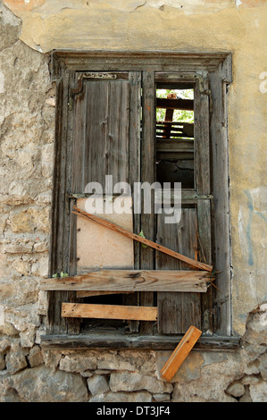 Alte Fenster Shutter und bröckelnden Mauer des verlassenen Hauses vernagelt. Stockfoto