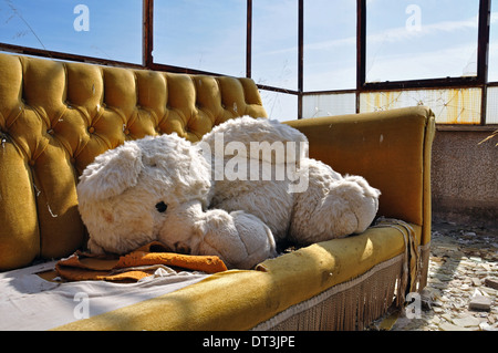 Vintage Teddybär und Couch im verlassenen Gebäude. Soziale Fragen. Stockfoto