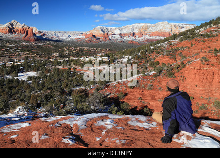 Ruhenden Wanderer schaut auf Schnee-gepunktete Sedona, Arizona von Overlook Punkt auf Mesa off-Road zum Flughafen Stockfoto