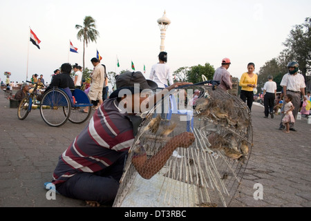 Ein Vogel-Verkäufer bereitet sich Vögel an Touristen auf der Uferpromenade in Phnom Penh, Kambodscha zu verkaufen. Stockfoto