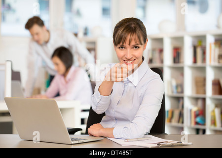 Glückliche Frau Schreibtisch lächelnd Punkt Finger computer Stockfoto