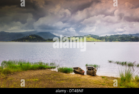 Zwei hölzerne Boote vertäut am Umiam See wie ein Monsun-Sturm über die Khasi Hügel in der Nähe von Shillong, Meghalaya, Indien droht. Stockfoto