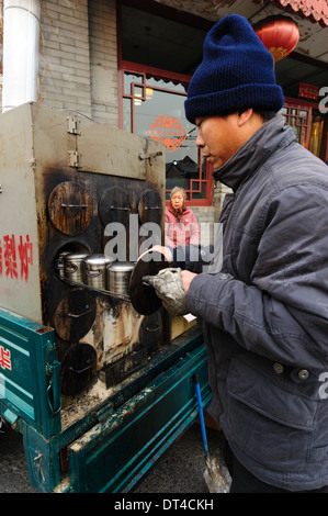 Man bereitet einen warmen Snack in einem mobilen Ofen. Peking, China Stockfoto