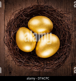 goldenen Eiern im Nest über hölzerne Hintergrund mit Text kopieren Stockfoto