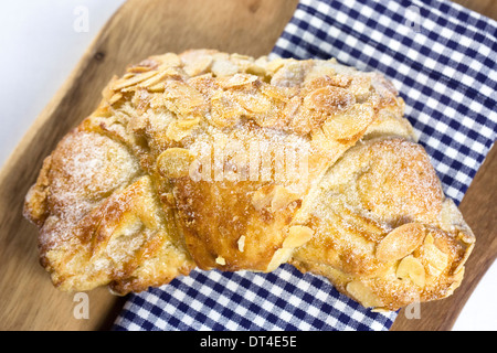 Mandel-Croissant. Einzelne halbmondförmige Blätterteig auf einem Holzbrett. Stockfoto