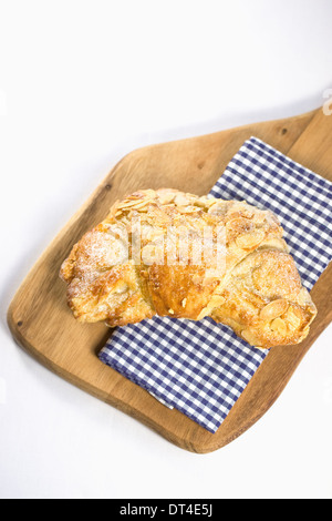 Mandel-Croissant. Einzelne halbmondförmige Blätterteig auf einem Holzbrett. Stockfoto