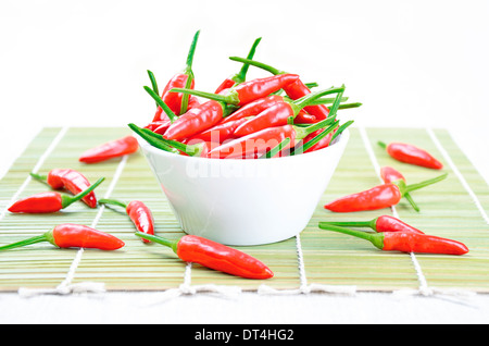 Rot-heiße Paprika in einer weißen Schüssel auf einer grünen Bambusmatte Stockfoto