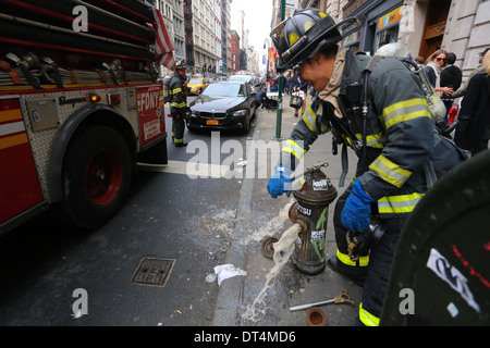 Ein chinesisch-amerikanischer FDNY-Feuerwehrmann öffnet einen Hydranten in New York City Stockfoto
