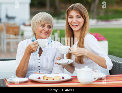 Erwachsene Mutter und Tochter trinken Tee oder Kaffee. Sie kommunizieren in einem Café draußen zu sitzen. Stockfoto