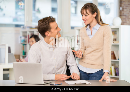 Geschäftsfrau Geschäftsmann fröhlich Schreibtisch sprechen Stockfoto
