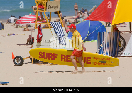 mittleren Alter Lebensretter tragen ein Surfbrett am manly Beach, Sydney, Australien Stockfoto