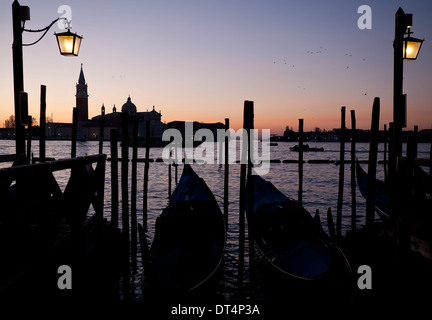 Schwarze Silhouetten der Gondeln am Sonnenaufgang in Venedig Himmel und San Giorgio Maggiore-Hintergrund Stockfoto