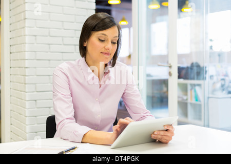 Brünette Frau mit Tablet Computer am Schreibtisch im Büro Stockfoto