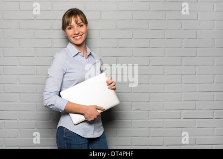 Porträt der jungen Frau mit Computer im Studio, auf der Suche Kamera Stockfoto