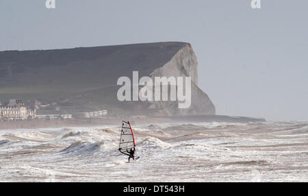 Ein Windsurfer kämpfen gegen die Wellen Gezeiten-Mühlen Strand Newhaven heute als Stürme weiterhin der South Coast of Britain Teig. Seaford Kopf Klippen in Ferne zu sehen Stockfoto