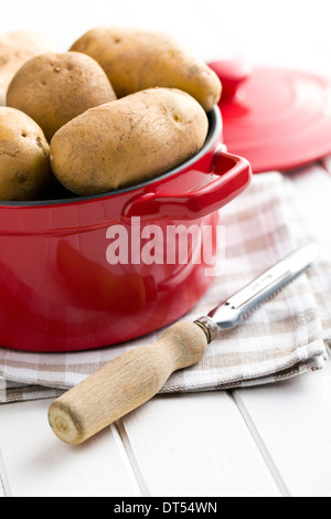 die rohen Kartoffeln und alten hölzernen Schäler Stockfoto