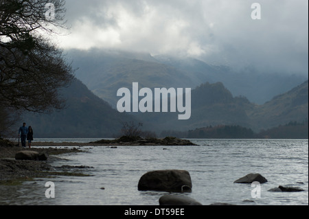 Ein romantisches Paar zu Fuß am Ufer des Derwent Water mit Borrowdale als einen schönen Hintergrund. Stockfoto