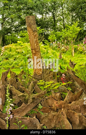 Stumpery im Garten des Burnby Hall, Pocklington, Yorkshire, mit Holz-Schnitzerei, Farne und Wildblumen. Stockfoto