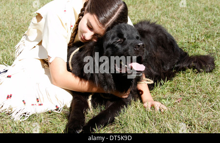 Native American Indian Mädchen umarmt einen schwarzen Hund Stockfoto