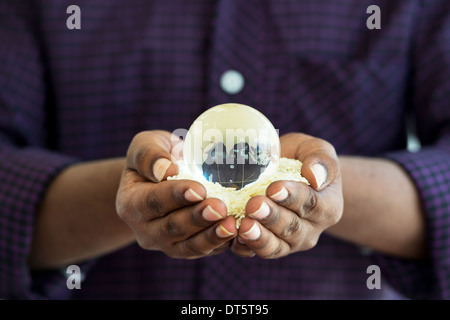 Indische mans Hände halten Reis mit einer Glaskugel, eine globale Nahrungsmittelkrise zu vertreten / Mangel Stockfoto