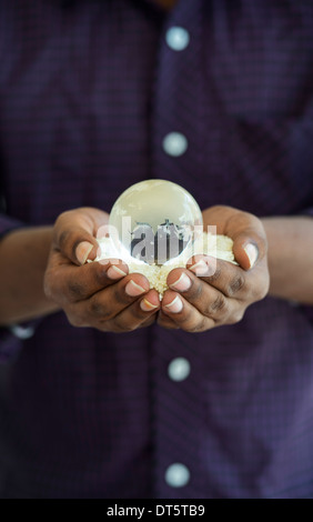 Indische mans Hände halten Reis mit einer Glaskugel, eine globale Nahrungsmittelkrise zu vertreten / Mangel Stockfoto