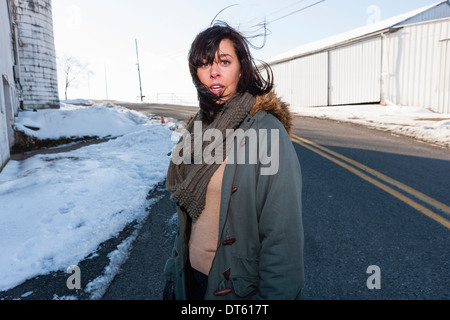 Junge Frau, die außen Wirtschaftsgebäude im winter Stockfoto