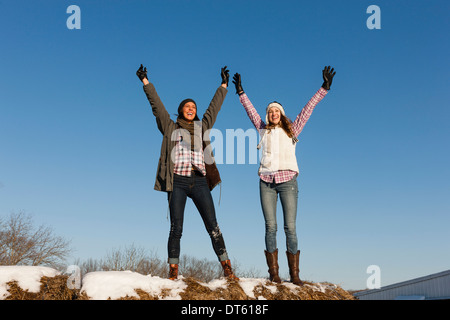 Zwei junge Frauen mit Armen angehoben auf Winter-Hügel Stockfoto