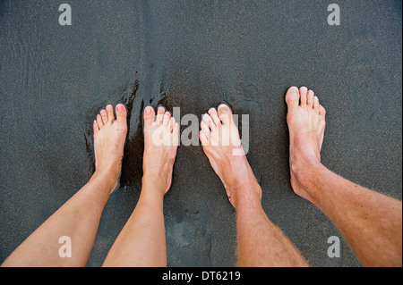 Paare von männlichen und weiblichen Füße auf schwarzem sand Stockfoto