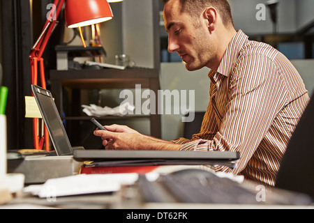 Geschäftsmann am Schreibtisch mit Handy Stockfoto