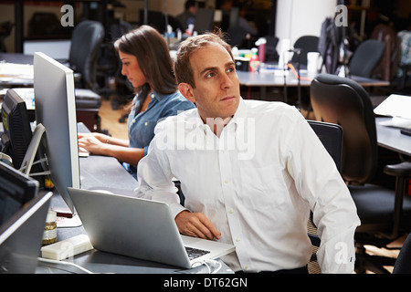 Mitte erwachsener Mann mit Laptop im Büro Stockfoto