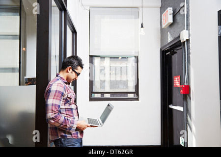 Junger Mann mit Laptop im Korridor Stockfoto