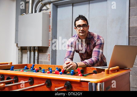 Porträt des jungen Mannes stützte sich auf Tischfußball Stockfoto