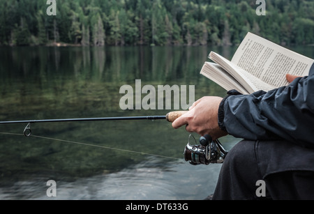 Mann Angeln mit Buch, Buntzen Lake, British Columbia, Kanada Stockfoto