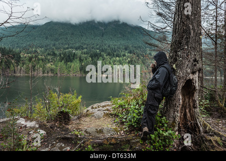 Mann, die wasserdichte Kleidung von Baum, Buntzen Lake, British Columbia, Kanada Stockfoto