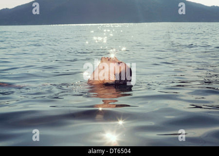 Junge Frau schwimmt auf Rückseite in Lake Attesee, Österreich Stockfoto