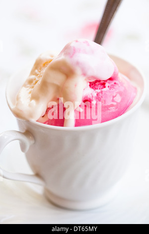 Nahaufnahme der Tasse mit Himbeer und Vanille-Eis und Löffel auf hellem Hintergrund Stockfoto