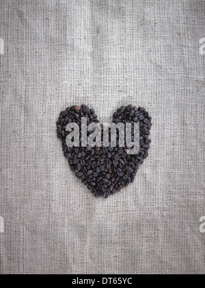 Bio Kaffeebohnen in Form eines Herzens auf einem Leinensack. Stockfoto